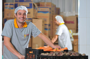 trabalhador com touca de cabelo sorrindo no estoque da empresa Master Kitchen
