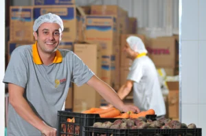 trabalhador com touca de cabelo sorrindo no estoque da empresa Master Kitchen 